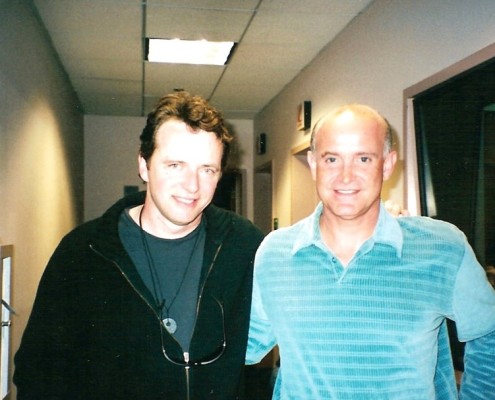 Two men standing next to each other in a hallway.