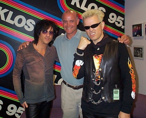 Three men posing for a picture in front of a radio station.