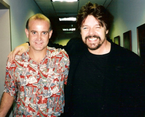 Two men standing next to each other in a hallway.