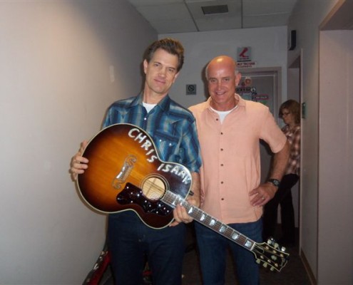 Two men standing next to each other holding an acoustic guitar.