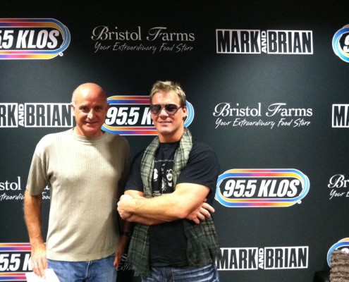 Two men posing for a picture in front of a radio station.