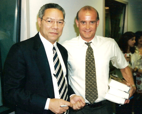 Two men standing next to each other holding books.