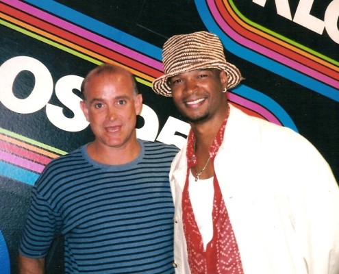 Two men posing for a photo in front of a colorful wall.