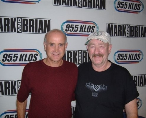 Two men posing for a photo in front of a radio station.