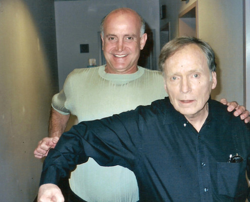 Two men standing next to each other in a hallway.