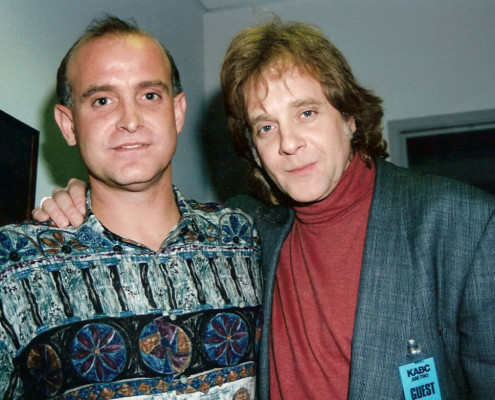 Two men posing for a photo in front of a wall.