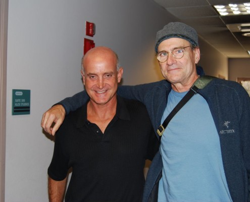 Two men standing next to each other in a hallway.