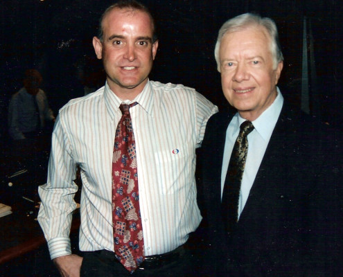 A man in a suit standing next to a man in a tie.