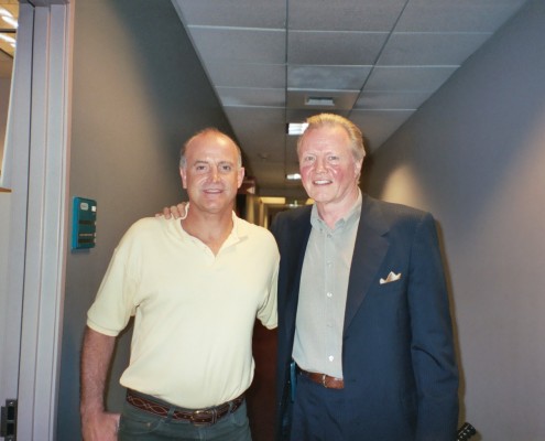 Two men standing next to each other in a hallway.