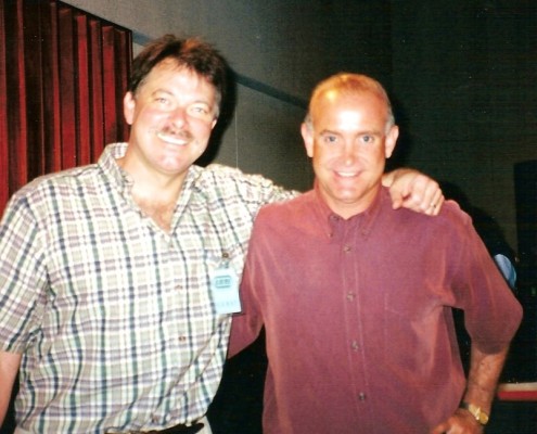 Two men standing next to each other in a recording studio.