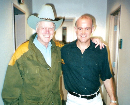 Two men standing next to each other in a hallway.