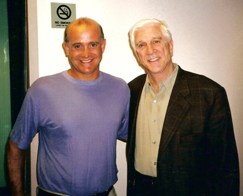 Two men posing for a picture in front of a wall.