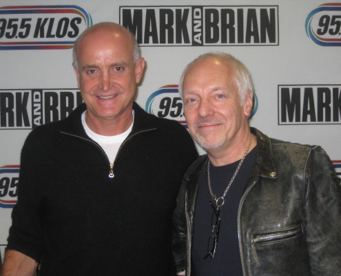 Two men posing for a photo in front of a radio station.