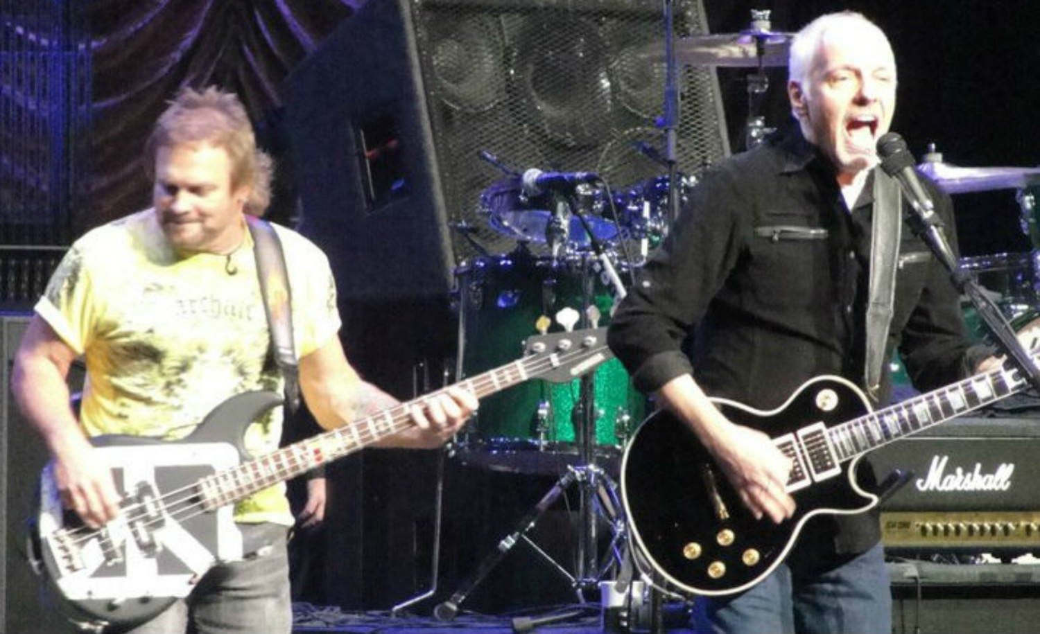 A man playing guitar and another man standing up