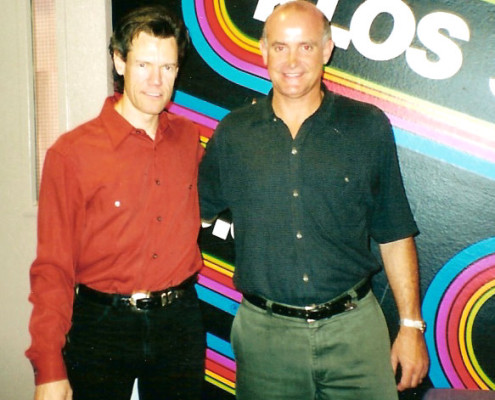 Two men standing next to each other in front of a radio station.