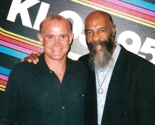 Two men posing for a photo in front of a radio station.