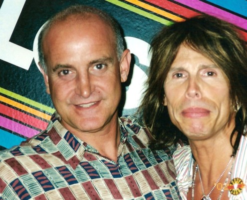 Two men posing for a photo in front of a colorful wall.