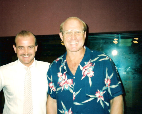 A man in a hawaiian shirt standing next to another man.