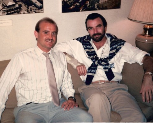 Two men sitting on a couch with ties on.