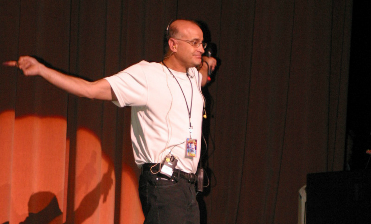 A man standing on a stage with his arms outstretched.