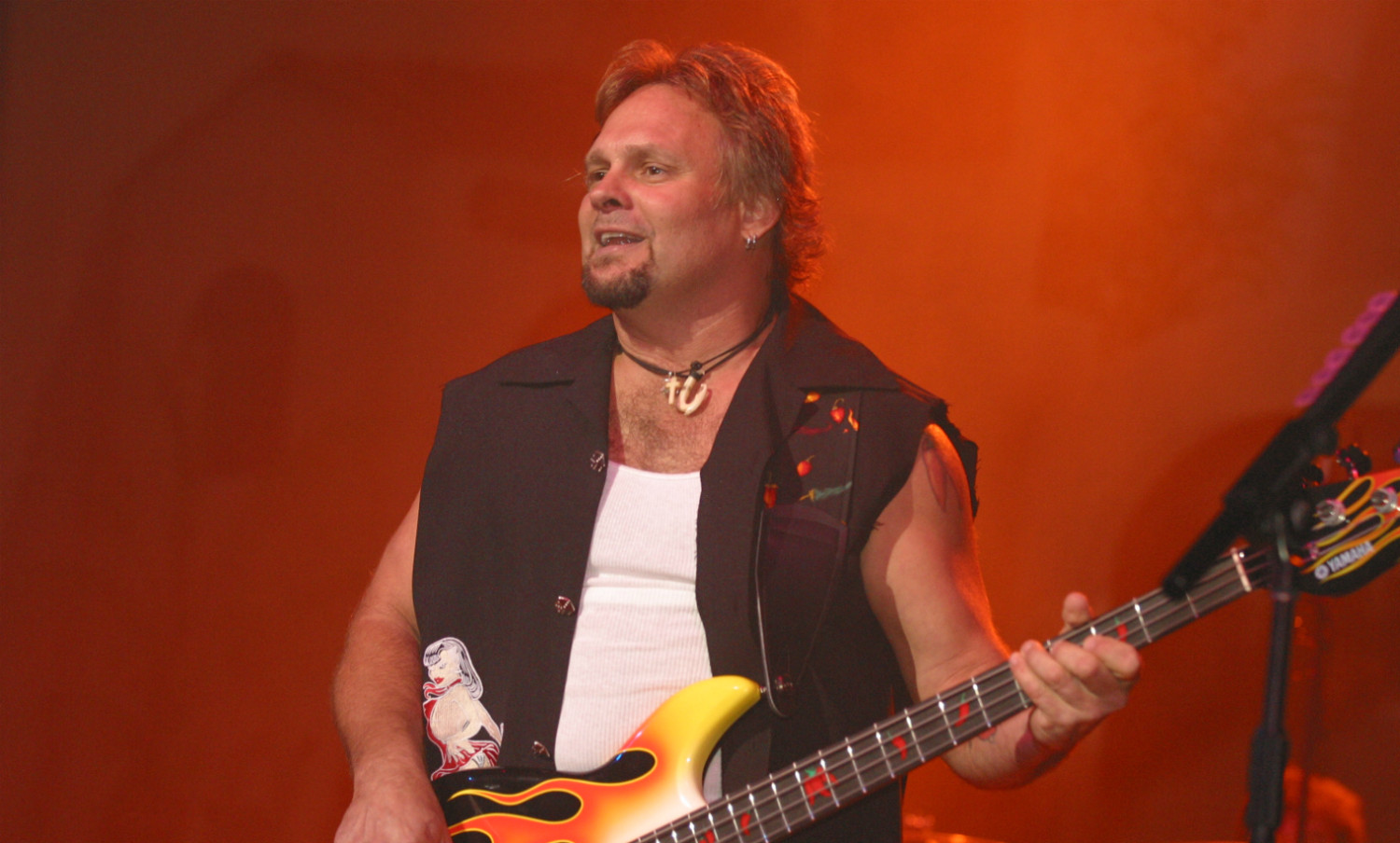 A man with long hair and a beard playing guitar.