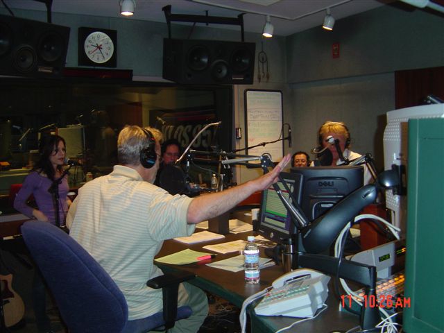 A man in headphones is pointing to the ceiling.