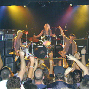 A band performing on stage with people watching.