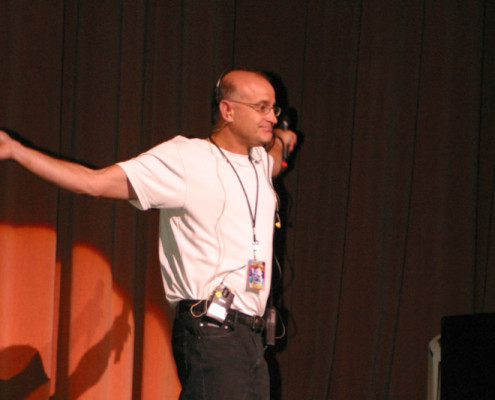 A man standing on stage with his arms outstretched.