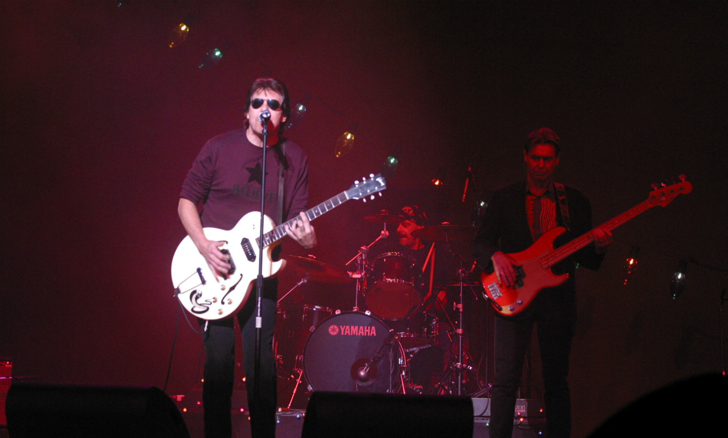 A man with a guitar and other people on stage