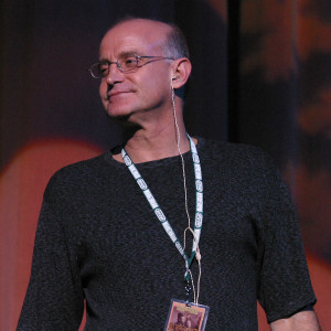 A man with glasses and a beard is standing on stage.