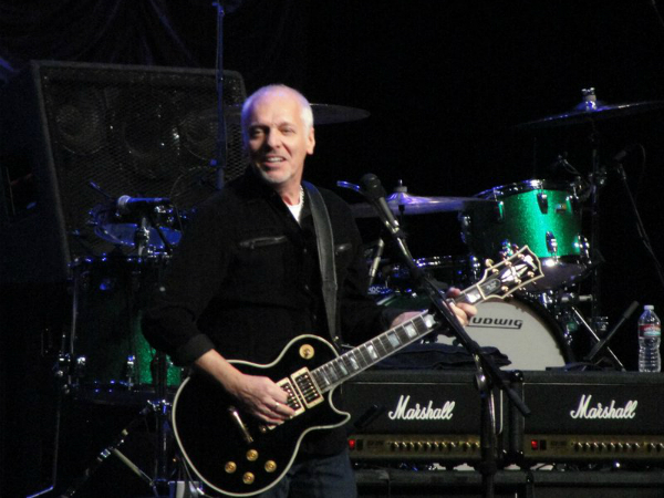 A man holding a guitar in front of some other people.