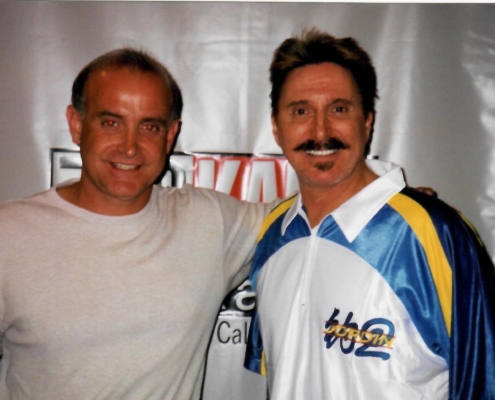 Two men posing for a picture in front of a baseball bat.