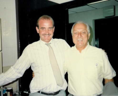 Two men standing next to each other in front of a mirror.